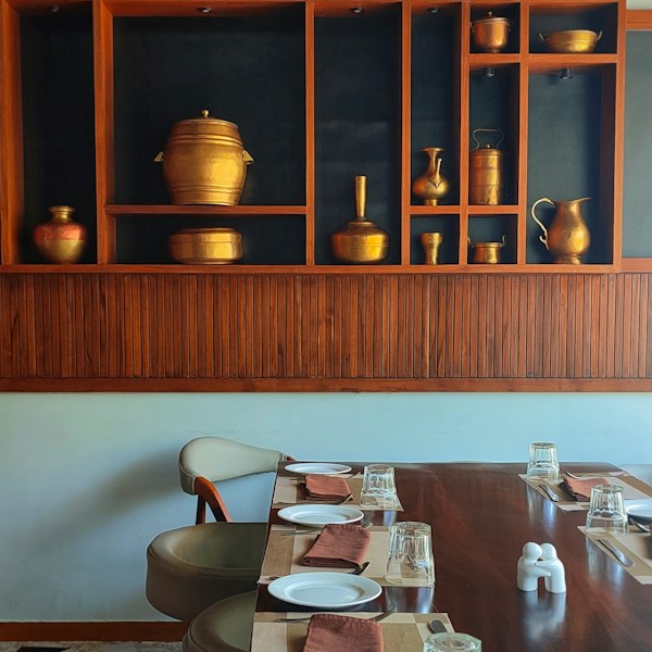 Dining table beneath shelves of copper vessels
