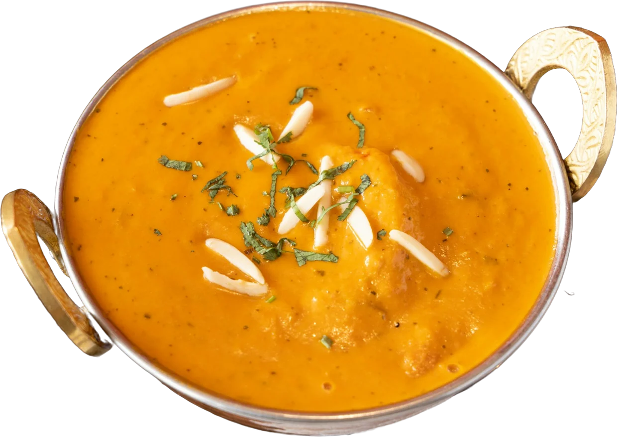 Creamy curry garnished with almonds and herbs in a handi with brass handles